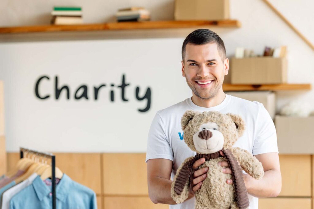 Man holding a teddy in front of a charity sign