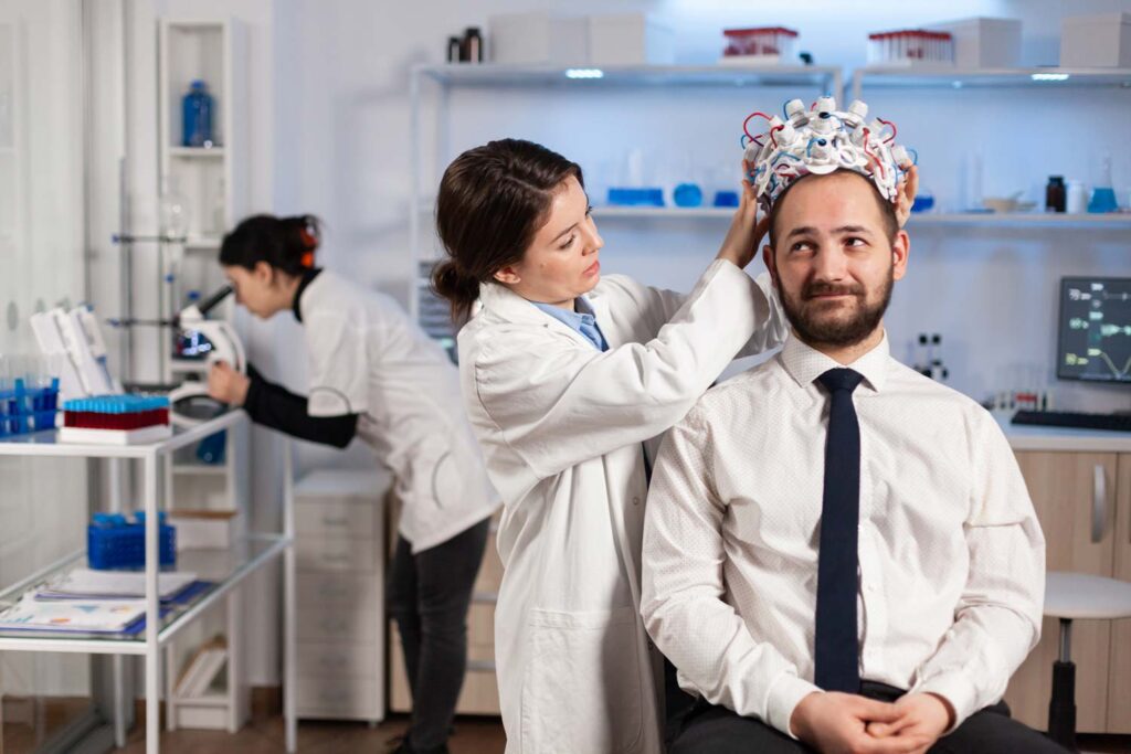 Man in a lab having some sort of contraption put on his head to read brain waves