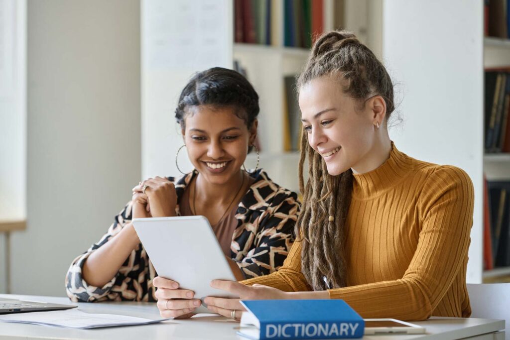 Girls using an electronic tablet, next to the dictionary